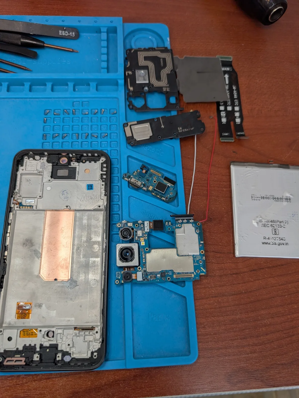 Smartphone démonté avec carte mère et batterie en réparation